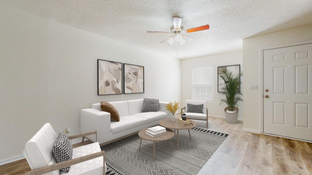A living room with a white couch, a wooden coffee table, and a ceiling fan.