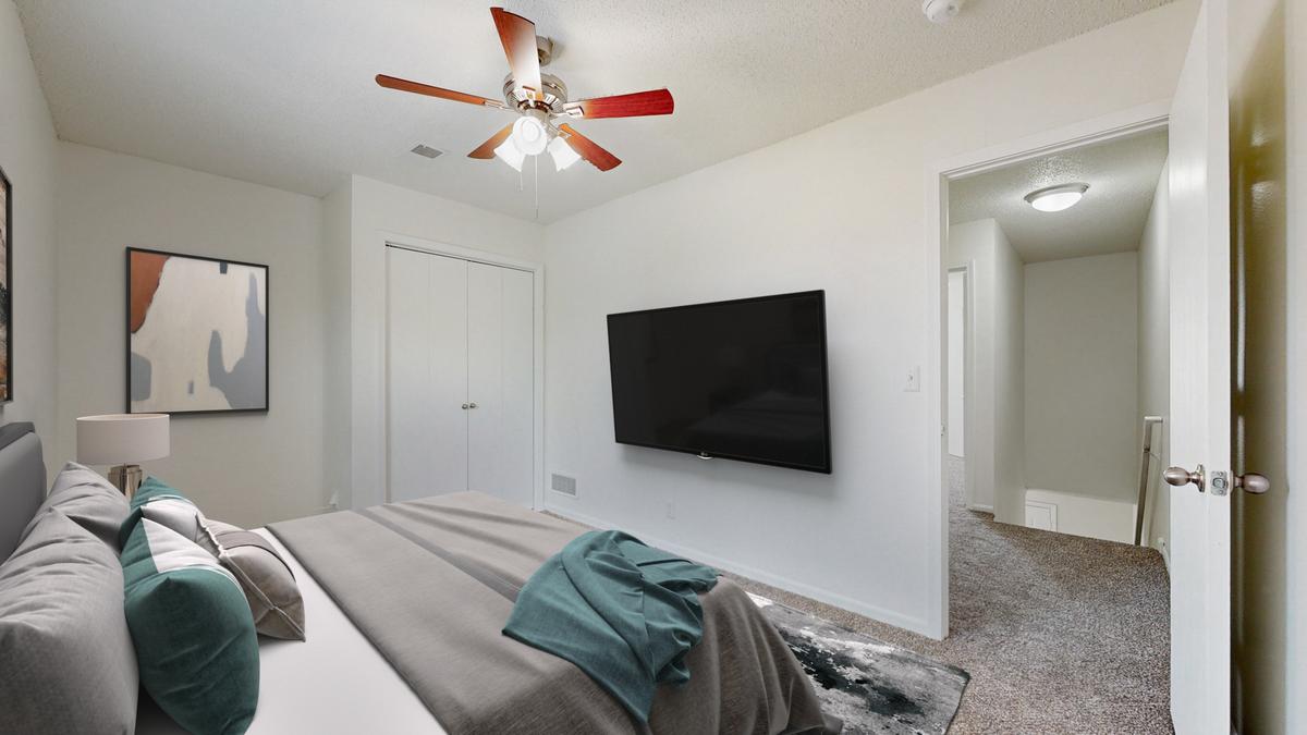 A living room with a grey couch and a black television.